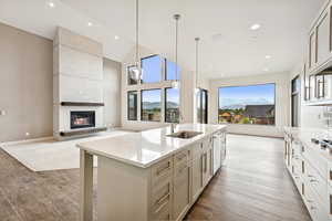 Kitchen with open floor plan, light stone counters, pendant lighting, a mountain view, and a large fireplace