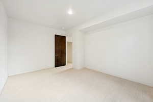 Unfurnished room featuring light carpet and baseboards