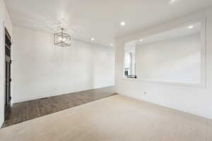 Unfurnished room with recessed lighting, wood finished floors, a chandelier, and carpet flooring