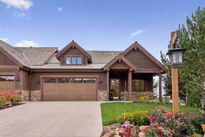 Craftsman inspired home featuring stone siding, a front yard, covered porch, and a garage