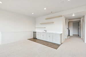 Kitchen with light colored carpet, recessed lighting, light countertops, open shelves, and stainless steel refrigerator