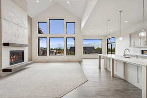 Unfurnished living room with a mountain view, a high end fireplace, high vaulted ceiling, recessed lighting, and light wood-style floors