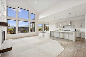 Unfurnished living room featuring high vaulted ceiling, a premium fireplace, recessed lighting, light wood-type flooring, and a mountain view
