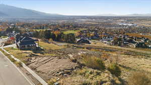 Aerial view of property and surrounding area featuring nearby suburban area and a mountain backdrop