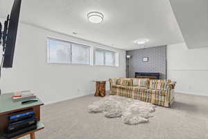 Sitting room with carpet flooring, a textured ceiling, and a fireplace