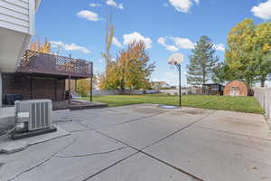 Fenced backyard with a wooden deck, a patio, and a shed