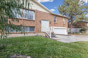 Rear view of house featuring a garage, brick siding, and driveway