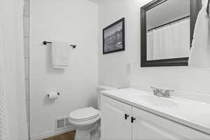 Full bath featuring a shower with shower curtain, vanity, and dark wood-type flooring