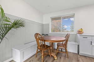 Dining room with wainscoting, light wood-style floors, breakfast area, and wooden walls