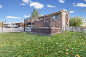 Back of property with a deck, a fenced backyard, and brick siding