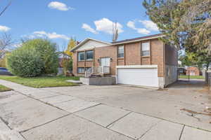 View of front facade with brick siding, driveway, an attached garage, and a front lawn