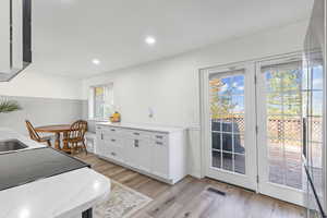 Kitchen with light stone countertops, white cabinetry, light wood-style flooring, recessed lighting, and black electric range