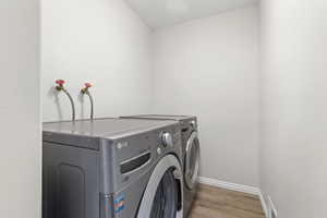 Laundry area featuring wood finished floors and separate washer and dryer