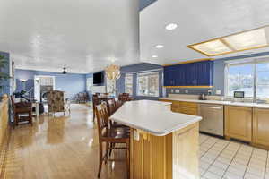 Kitchen featuring light countertops, open floor plan, stainless steel dishwasher, a chandelier, and a kitchen island