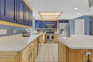 Kitchen with light tile patterned floors, light countertops, stainless steel appliances, recessed lighting, and a center island