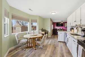 Kitchen featuring a peninsula, white cabinetry, light granite countertops, and backsplash