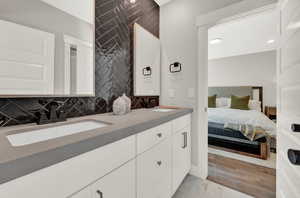 Bathroom featuring backsplash, double vanity, light wood finished floors, and recessed lighting