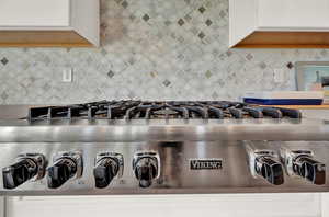 Kitchen view of stainless steel gas stovetop and tasteful backsplash
