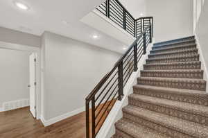 Stairway featuring wood finished floors, recessed lighting, and a high ceiling