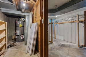 Unfinished below grade area featuring strapped water heater and wood walls