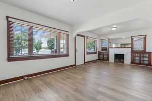 Unfurnished living room featuring light wood-style flooring, arched walkways, and a fireplace