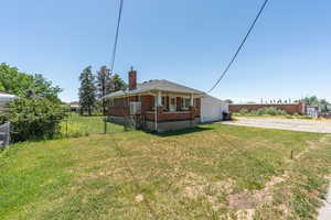 Back of property featuring brick siding, concrete driveway, a chimney, and an attached garage