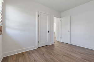 Unfurnished bedroom featuring wood finished floors and baseboards