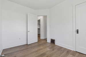 Unfurnished bedroom featuring wood finished floors and baseboards