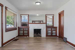 Unfurnished living room featuring wood finished floors and a brick fireplace