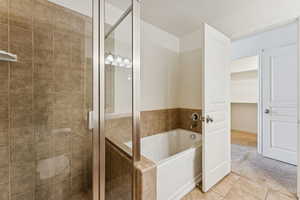 Full bath featuring a stall shower, a bath, tile patterned flooring, carpet, and a spacious closet