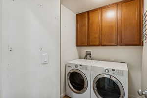 Washroom with washer and clothes dryer, cabinet space, and a textured ceiling