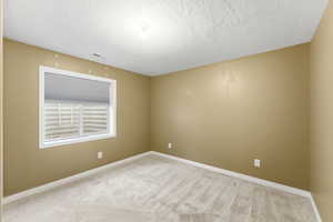 Empty room with carpet flooring and a textured ceiling