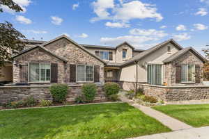 Craftsman house with stone siding, stucco siding, and a front yard