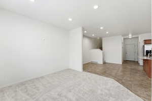 Unfurnished living room featuring recessed lighting, light colored carpet, and light tile patterned flooring
