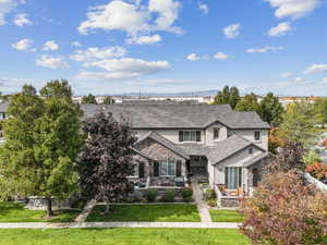 View of front facade featuring a front yard, stucco siding, stone siding, a high end roof, and a mountain view