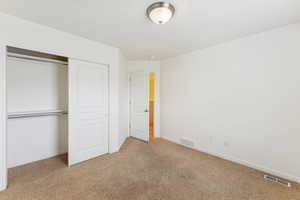 Unfurnished bedroom with light carpet and a closet