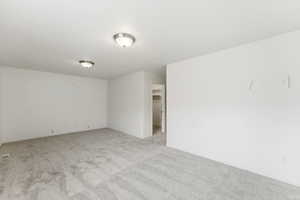 Unfurnished room featuring light carpet and baseboards