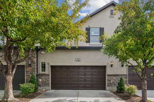 Traditional-style home with stone siding, stucco siding, concrete driveway, and a garage