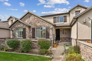 View of front of home featuring stucco siding, stone siding, and a porch