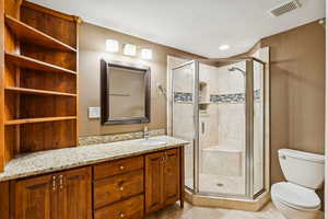 Full bathroom featuring vanity, a stall shower, a textured ceiling, and light tile patterned floors