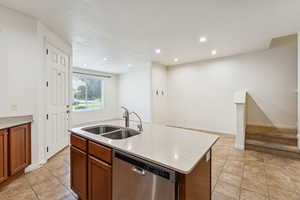 Kitchen with dishwasher, a kitchen island with sink, brown cabinets, light tile patterned floors, and recessed lighting