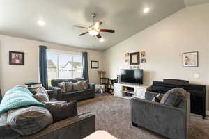 Carpeted living area featuring vaulted ceiling, ceiling fan, and recessed lighting