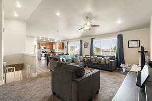 Carpeted living room featuring vaulted ceiling, a ceiling fan, wood finished floors, and recessed lighting