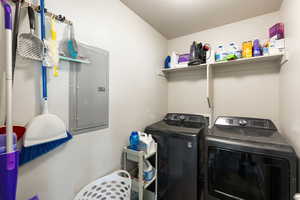 Laundry room with electric panel and washer and dryer