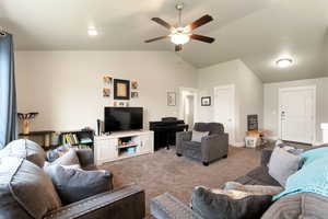 Living room with lofted ceiling, carpet, and a ceiling fan