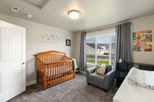 Carpeted bedroom featuring a crib and baseboards