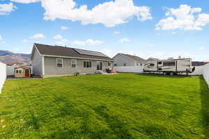 Back of house with a fenced backyard, solar panels, and a patio