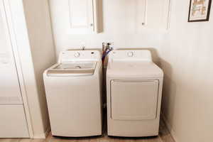 Washroom featuring a heating unit, washing machine and dryer, and cabinet space