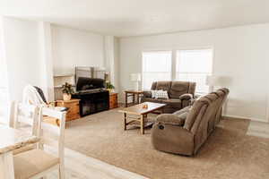 Living room with light wood-type flooring and light colored carpet