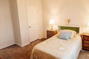 Bedroom featuring dark carpet and baseboards